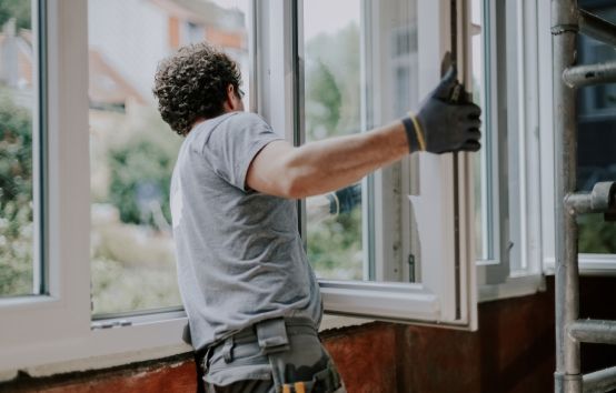Contractor installing a new white window frame